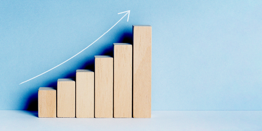 A wooden block graph with an arrow pointing up. The chart shows increasing spending, with the blocks representing different spending points.